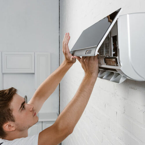 A Man Changes Filter on a Ductless Air Conditioner.