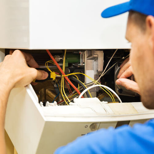 A Technician Repairs a Central Heating Unit.