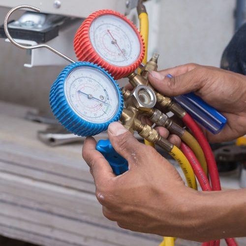 Hands Holding Manometer to Measure How Much Refrigerant Is Needed.